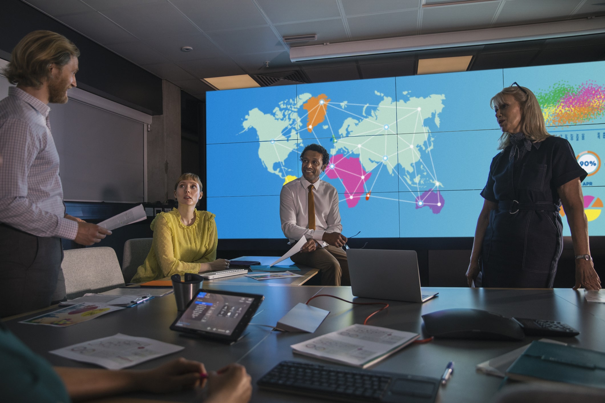 Presenting Data Against an Information Wall A global sustainability team meeting in a conference room in front of a world map.
