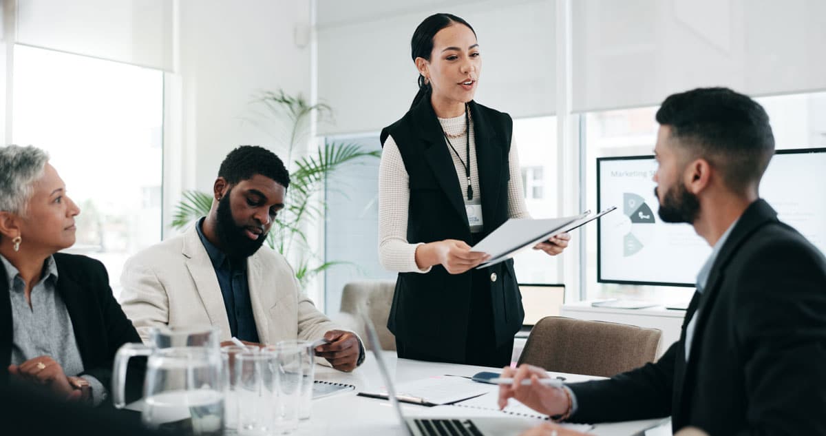 A manager leads a team meeting around a conference table.